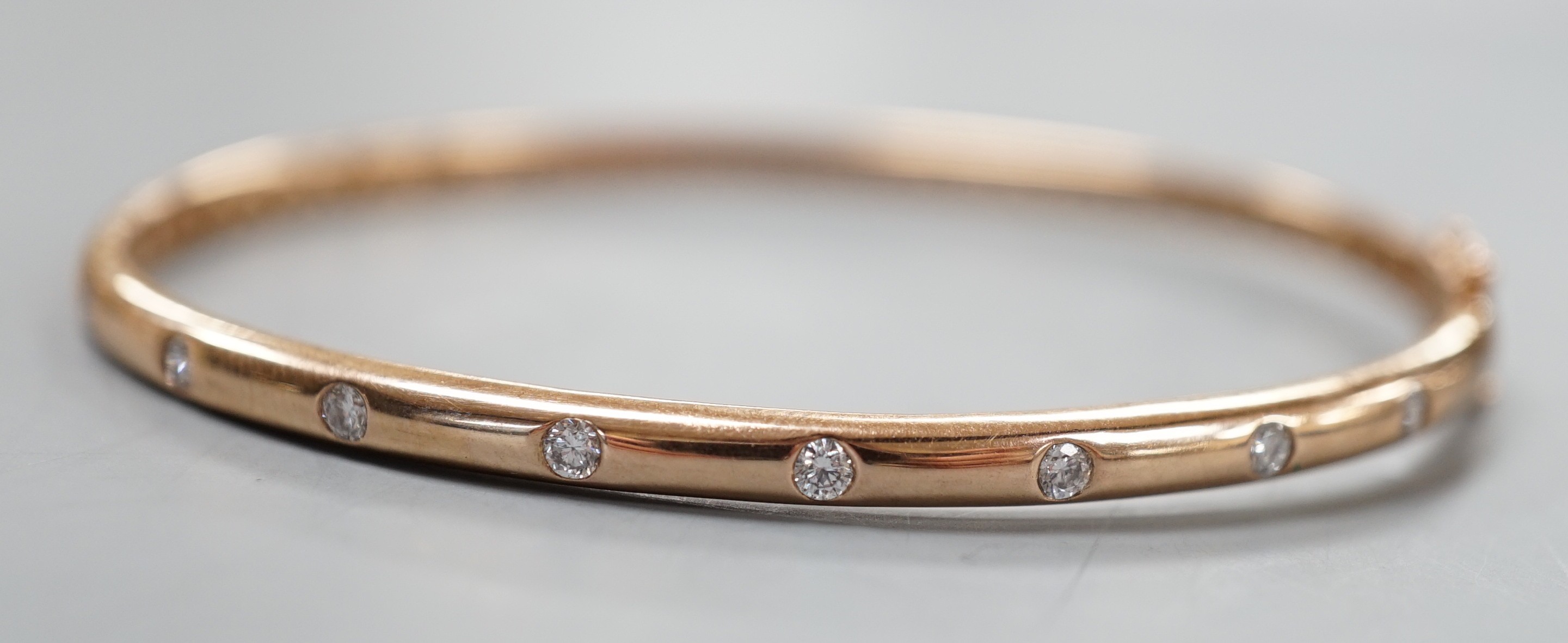 A modern 9k and nine stone gypsy set diamond hinged bangle, interior diameter 60mm, gross weight 9.3 grams.